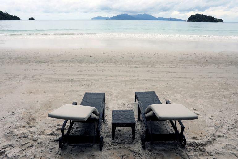Empty beach with two vacant lounge chairs