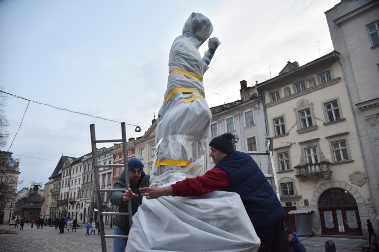 Workers wrap a statue to protect it in case of possible shelling in Lviv