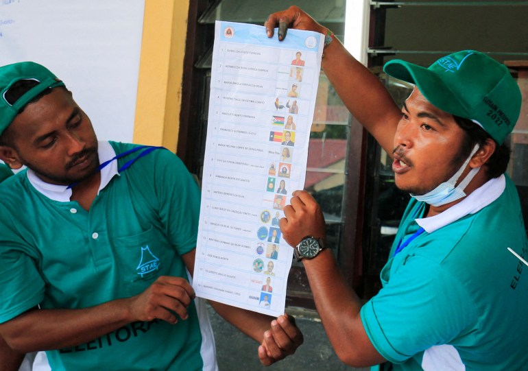 Two male election workers hold up ballot tallies during counting in the first round of Timor's election in March
