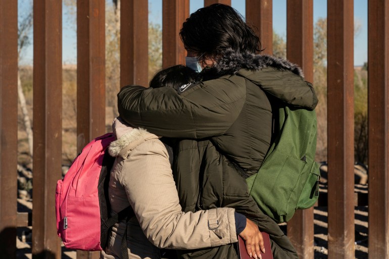 Asylum seekers hug at US-Mexico border wall