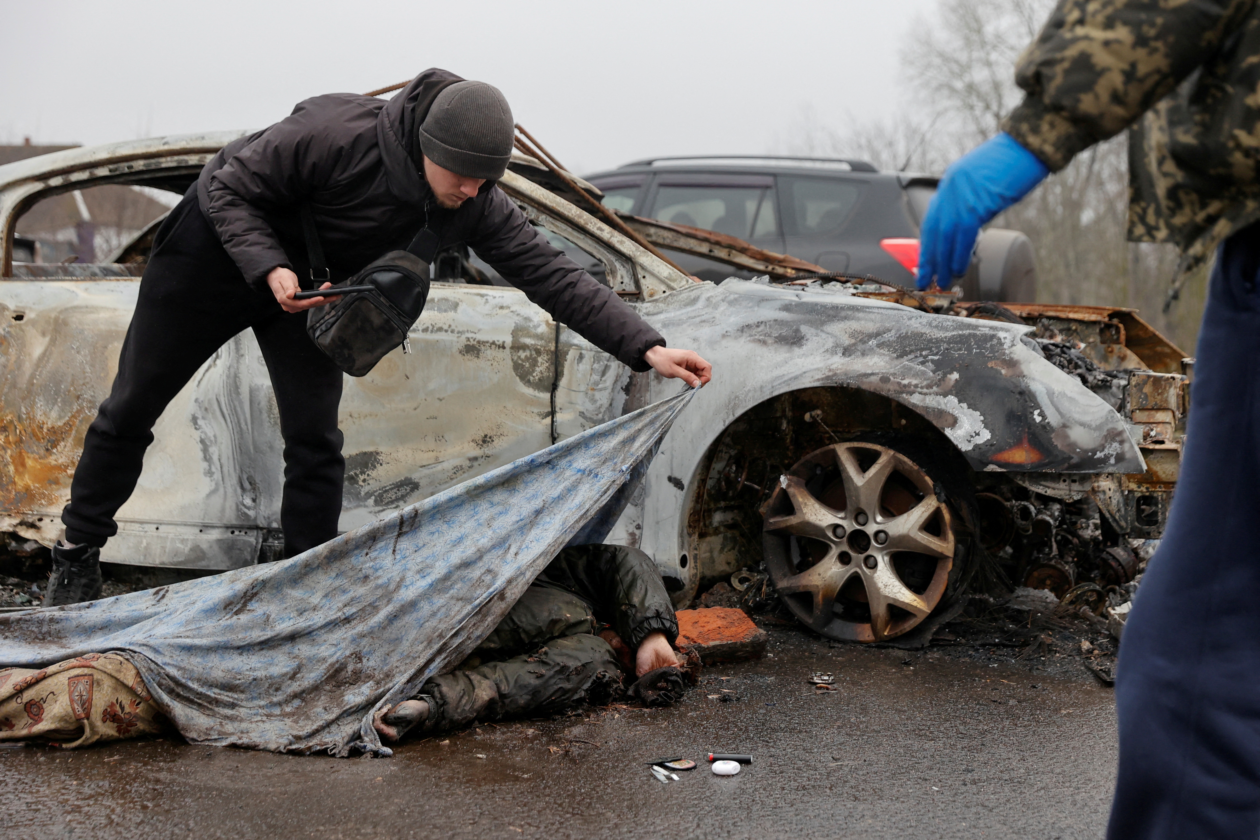 Um funcionário de um serviço funerário descobre um corpo de civil morto, enquanto o ataque da Rússia à Ucrânia continua, na vila de Nova Basan, na região de Chernihiv, Ucrânia, em 1º de abril de 2022.