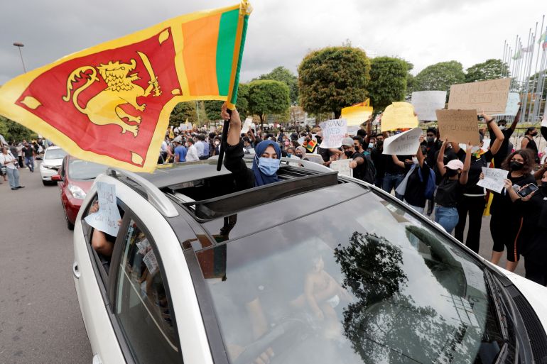 A woman waves a Sri Lankan flag from inside a car