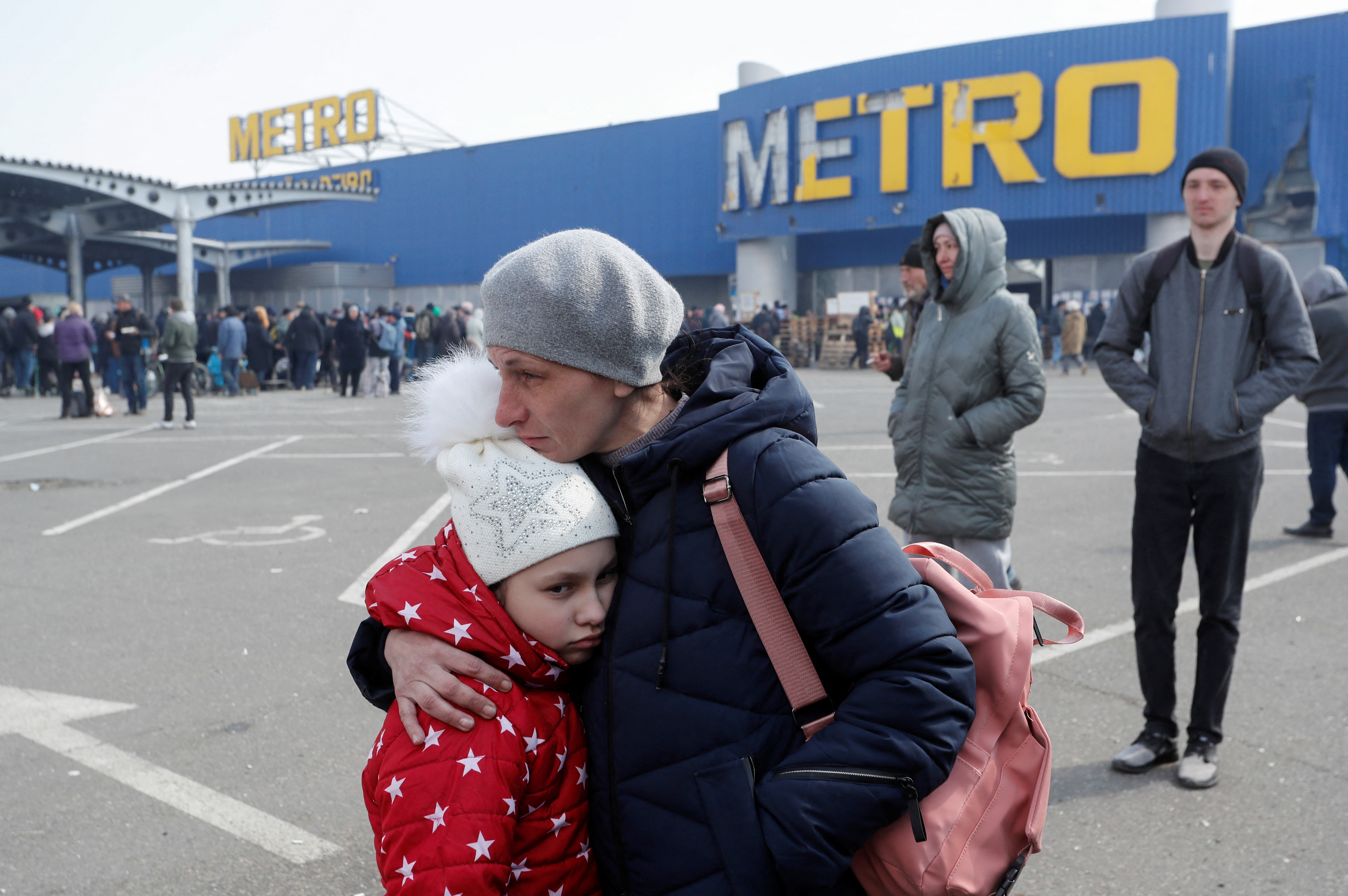Uma mulher abraça sua filha enquanto espera um ônibus em Mariupol, na Ucrânia.