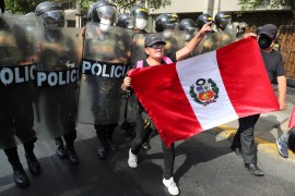 A demonstrator with a Peruvian flag marches in front of riot police in Lima, Peru.
