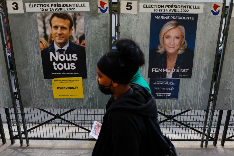 People walk past official campaign posters of Macron and Le Pen