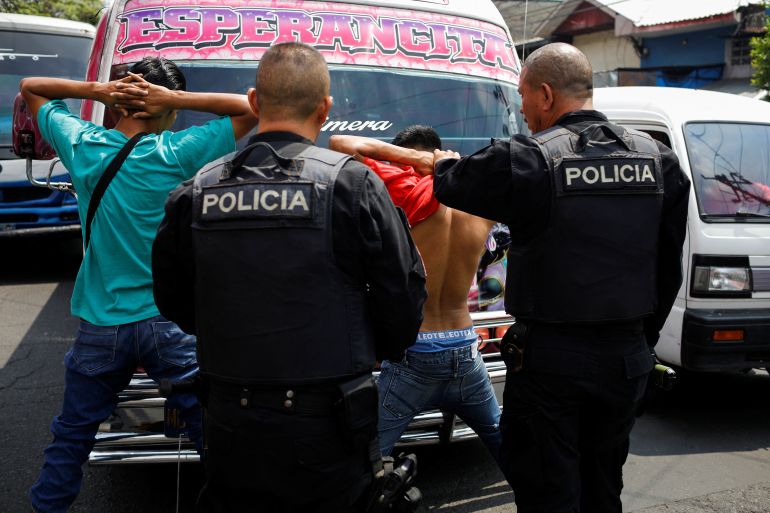Police officers search two men in El Salvador