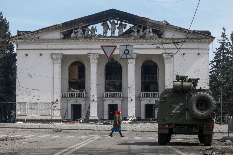 A woman walks next to an armoured vehicle of pro-Russian troops the building of a theatre destroyed in the course of Ukraine-Russia conflict in the southern port city of Mariupol, Ukraine April 10, 2022. REUTERS/Alexander Ermochenko TPX IMAGES OF THE DA