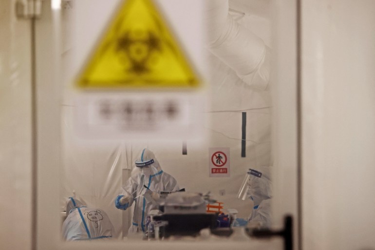 Workers in hazmat suits testing samples for COVID-19 in a Chinese lab