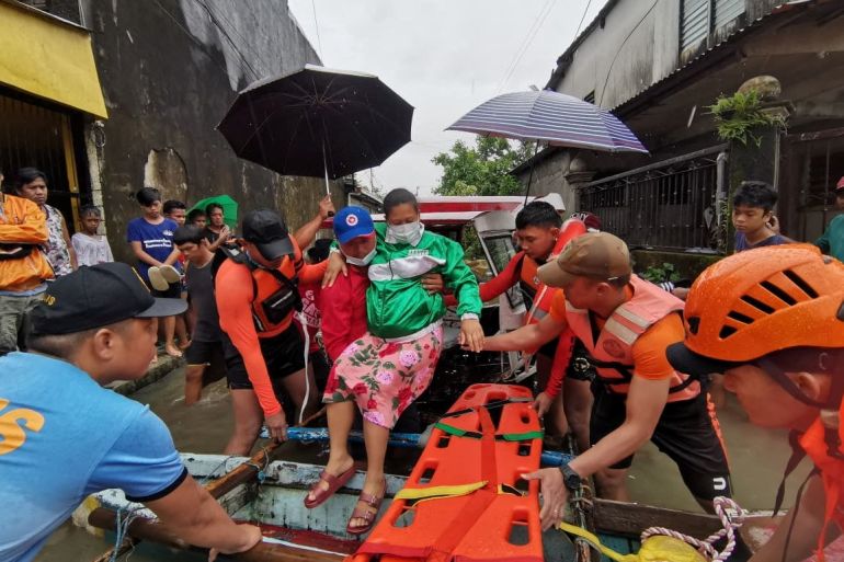 Officials help a woman into a raft amid heavy rain in Leyte province, Philippines.