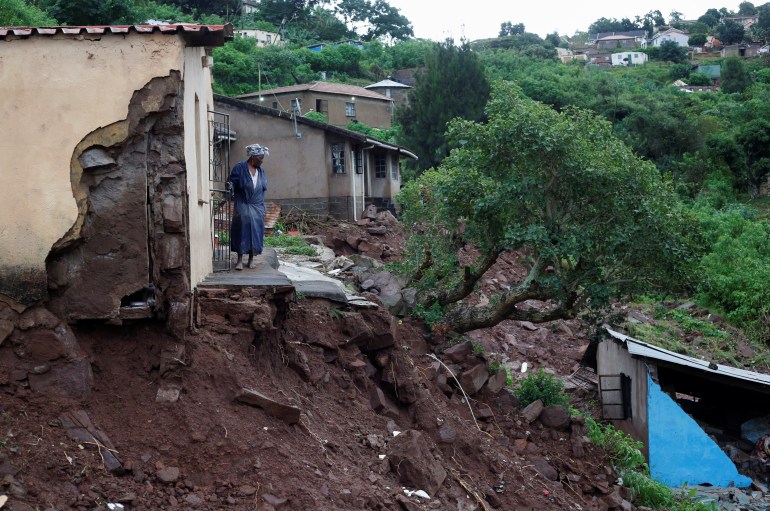 A woman stands at her front door after heavy rains caused flood damage in KwaNdengezi, Durban