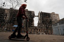 FILE PHOTO: A boy rides a scooter near a building destroyed during Ukraine-Russia conflict in the southern port city of Mariupol, Ukraine April 14, 2022. REUTERS/Alexander Ermochenko/File Photo