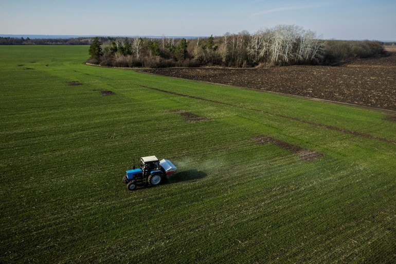 Pemandangan udara menunjukkan sebuah traktor menyebarkan pupuk di ladang gandum dekat desa Yakovlivka setelah dihantam oleh pemboman udara di luar Kharkiv, saat serangan Rusia di Ukraina berlanjut.