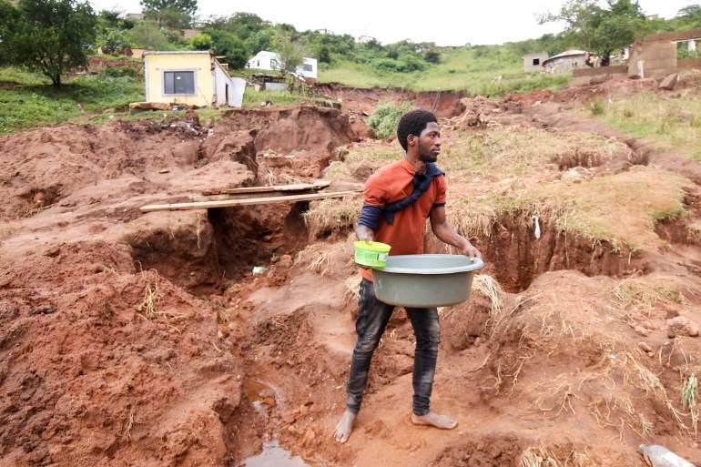 Mthandi Sibiya collects water near what remains of his home which collapsed while he was sleeping due flooding in Mzinyathi near Durban, South Africa,