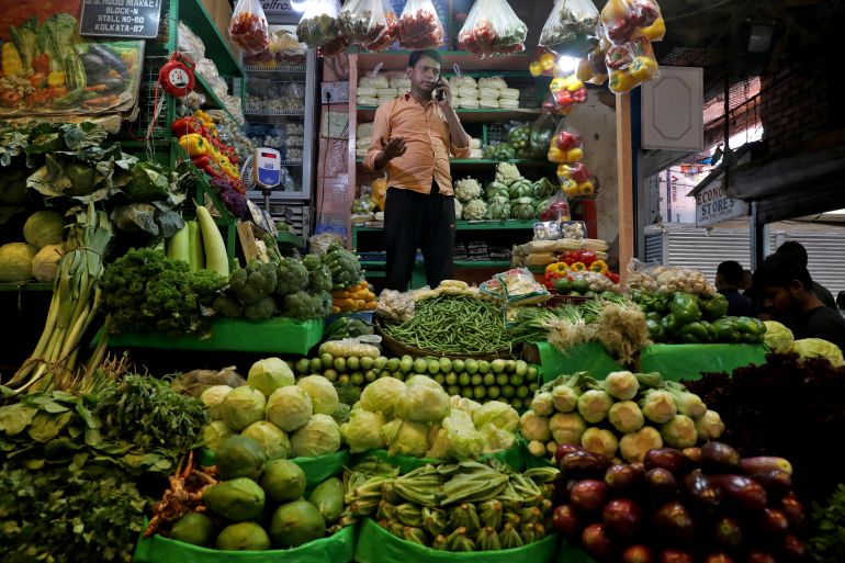 Debashis Dhara, a vegetable vendor, speaks on his mobile phone at a retail market area in Kolkata, India