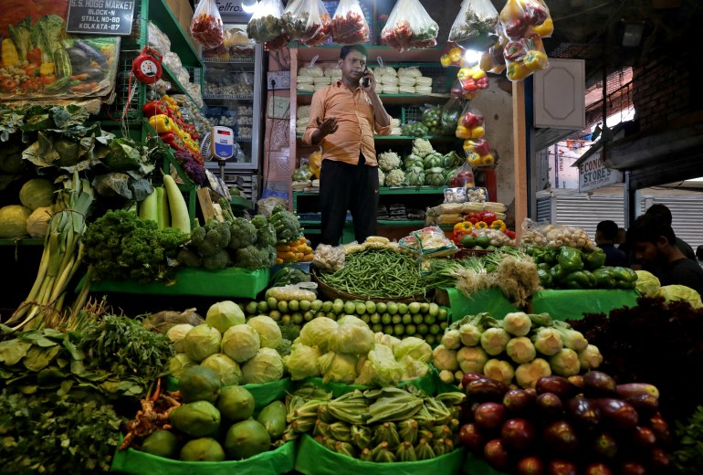 a vegetable vendor, speaks on his mobile phone at a retail market area in Kolkata, India