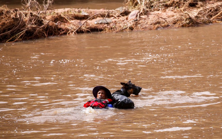 A search and rescue team member looks for bodies with the help of a dog, following torrential rains that triggered floods and mudslides,