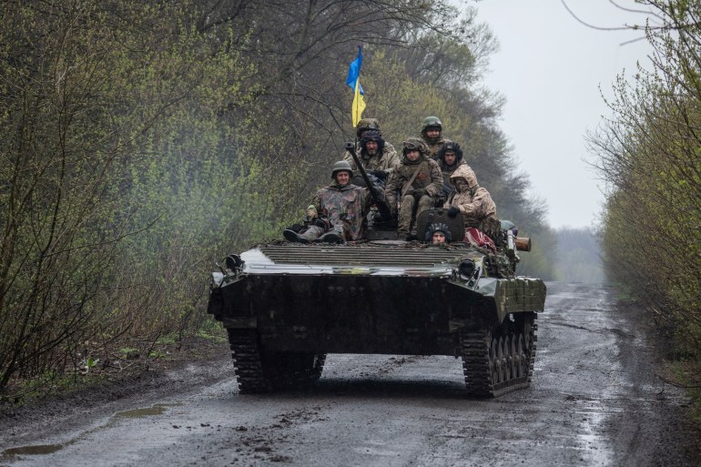 Ukrainian servicemen ride atop an armoured fighting vehicle