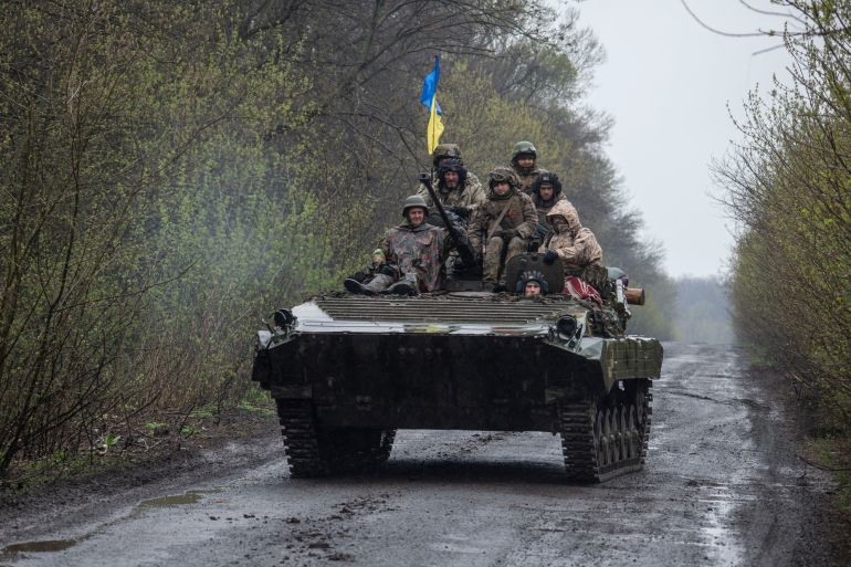 Ukrainian servicemen ride atop an armoured fighting vehicle