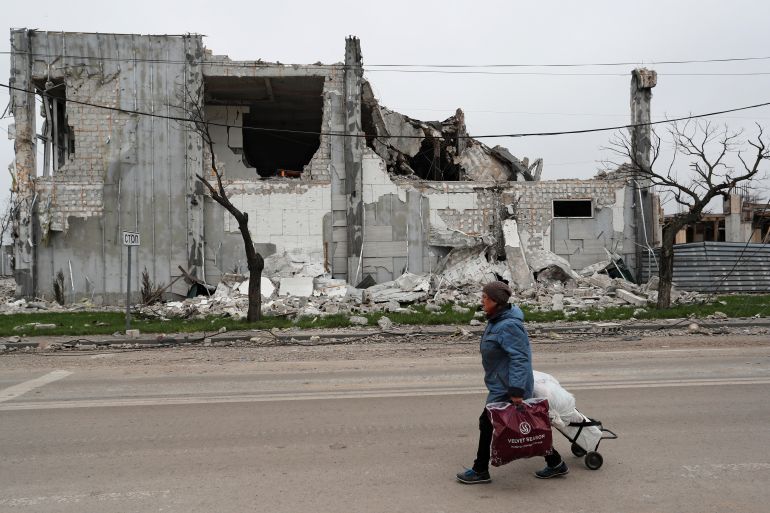 A local resident walks past a building destroyed during Ukraine-Russia conflict in the southern port city of Mariupol, Ukraine.