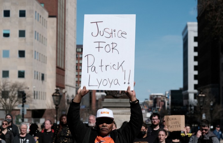 Bir protestocu Patrick Lyoya için Adalet yazan bir pankart tutuyor