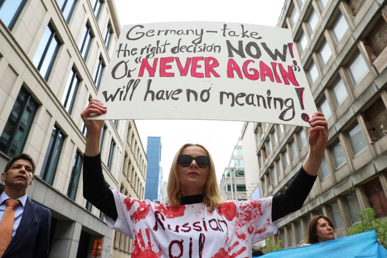 A demonstrator holds a banner as Climate activists protest in front of the German Embassy in Brussels