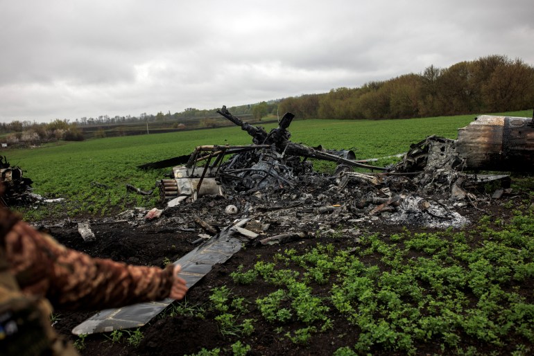 A Ukrainian soldier gestures towards a destroyed Russian helicopter in the outskirts of the village of Mala Rohan, amid Russia's invasion of Ukraine, in Kharkiv region, Ukraine, April 20, 2022. 