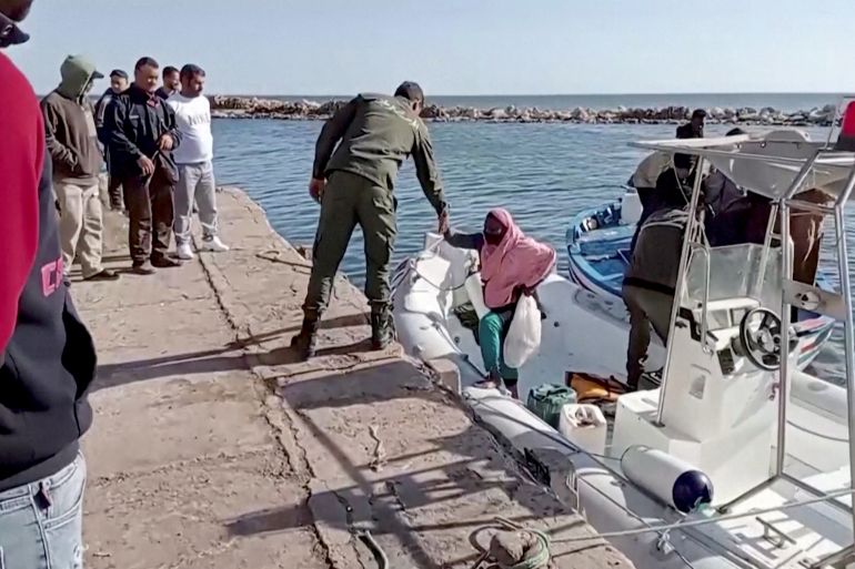 Man helps migrant off boat and onto shore