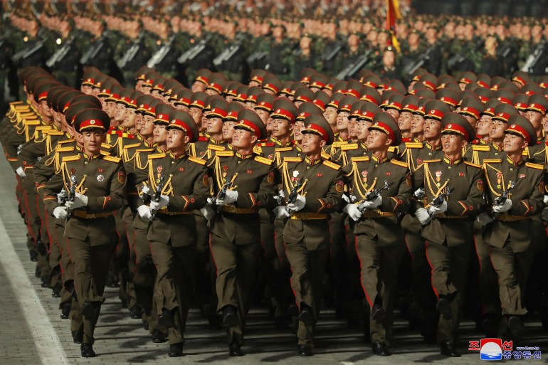 North Korean soldiers in green uniforms march in Monday night's parade in Kim Il Sung Square