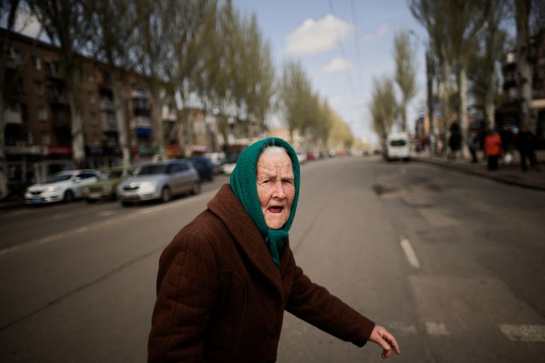 An elderly Ukrainian woman walks along a street, amid Russia's invasion of Ukraine, in the town of Kryvyi Rih