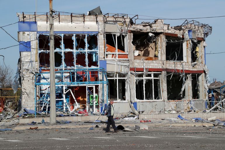 A man is seen walking near a destroyed building in Mariupol