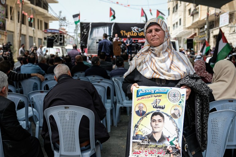 A mother of a Palestinian prisoner holds a poster with his photo.