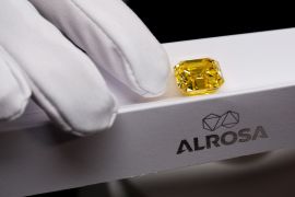 a gloved hand showing a yellow diamond