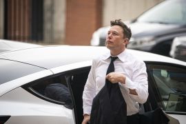 Elon Musk, chief executive officer of Tesla Inc., in a white shirt, dark tie carrying a jacket