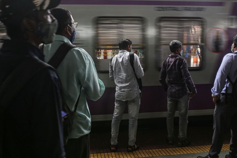 Passengers wait as a train arrives at Dadar railway train station in Mumbai, India