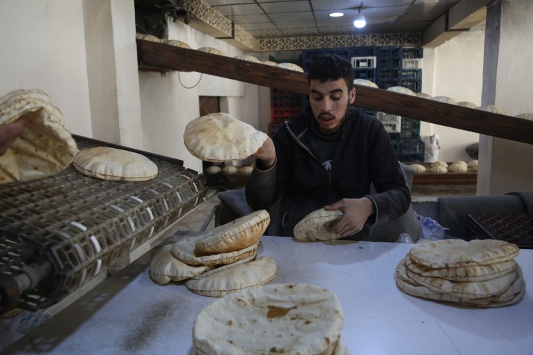 Man holds loaves of bread at bakery in Idlib