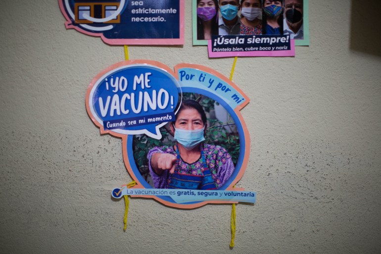 Un cartel en español que dice "Me vacunaré cuando sea mi momento.  Para ti y para mi.  La vacunación es gratuita, segura y voluntaria" Cuelga en la ciudad maya Tz'utujil de Santiago Atitlan