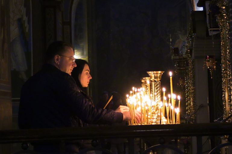A Ukrainian couple lights candles on Holy Saturday in St. Michael's Monastery in Kyiv [Mansur Mirovalev/Al Jazeera]