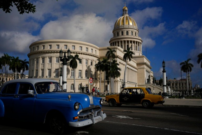 A vintage Russian-made Lada car, right, and an American-made classic car drive past the Capitol in Havana, Cuba