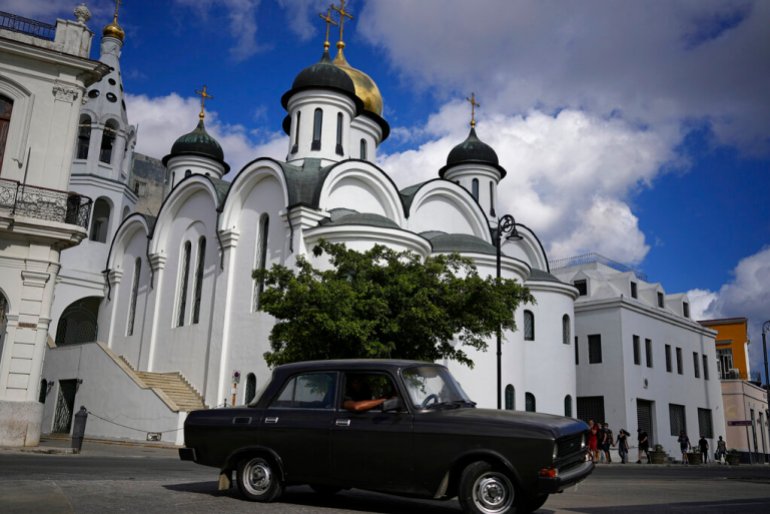 A vintage Russian-made Lada car drives past the Russian Orthodox Cathedral of Our Lady of Kazan in Havana, Cuba