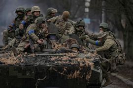 Ukrainian servicemen climb on a fighting vehicle outside Kyiv, Ukraine, Saturday, April 2, 2022. As Russian forces pull back from Ukraine's capital region, retreating troops are creating a "catastrophic" situation for civilians by leaving mines around homes, abandoned equipment and "even the bodies of those killed," President Volodymyr Zelenskyy warned Saturday. (AP Photo/Vadim Ghirda)