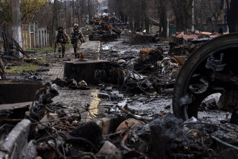 Soldiers walk amid destroyed Russian tanks in Bucha, on the outskirts of Kyiv, Ukraine