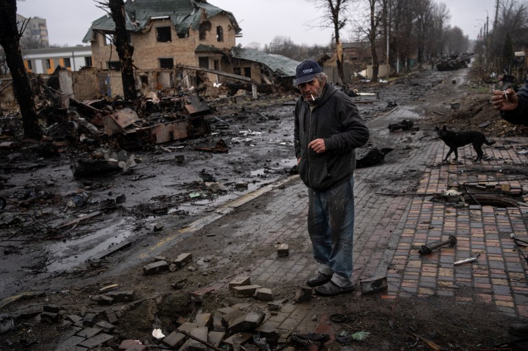Konstyantyn, de 70 años, fuma un cigarrillo en medio de tanques rusos destruidos en Bucha, en las afueras de Kiev.