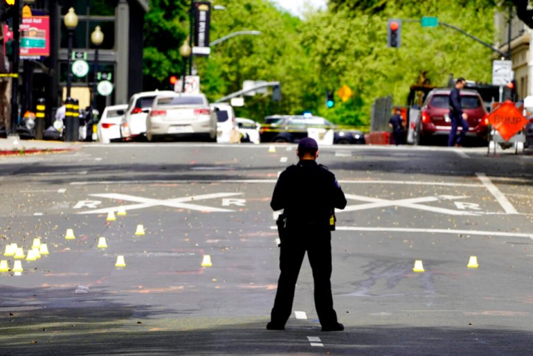 A Sacramento City Police Officer stands near a field of evidence markers after a mass shooting In Sacramento.