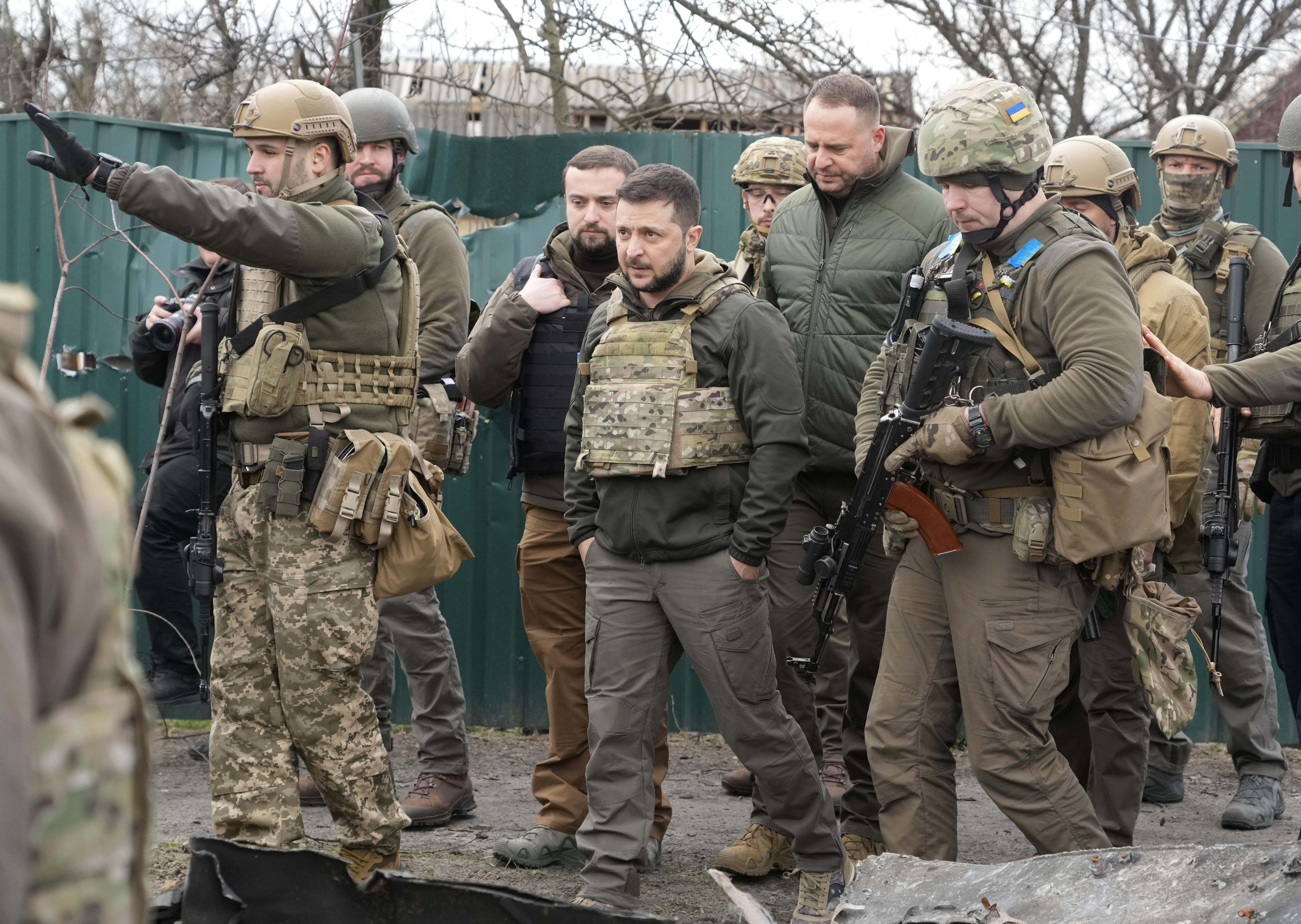 Volodomyr Zelenskyy in fatigues and bullet proof vest visits the town of Bucha accompanied by Ukrainian soldiers.