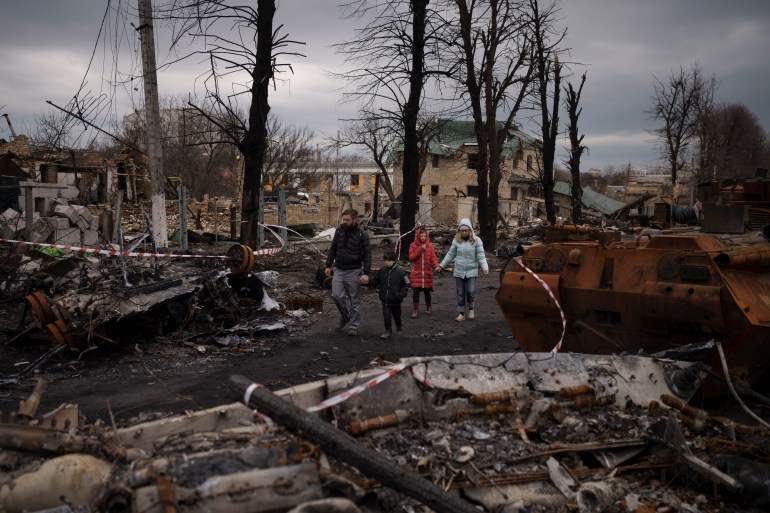 A family walks amid destroyed Russian tanks in Bucha, on the outskirts of Kyiv, Ukraine