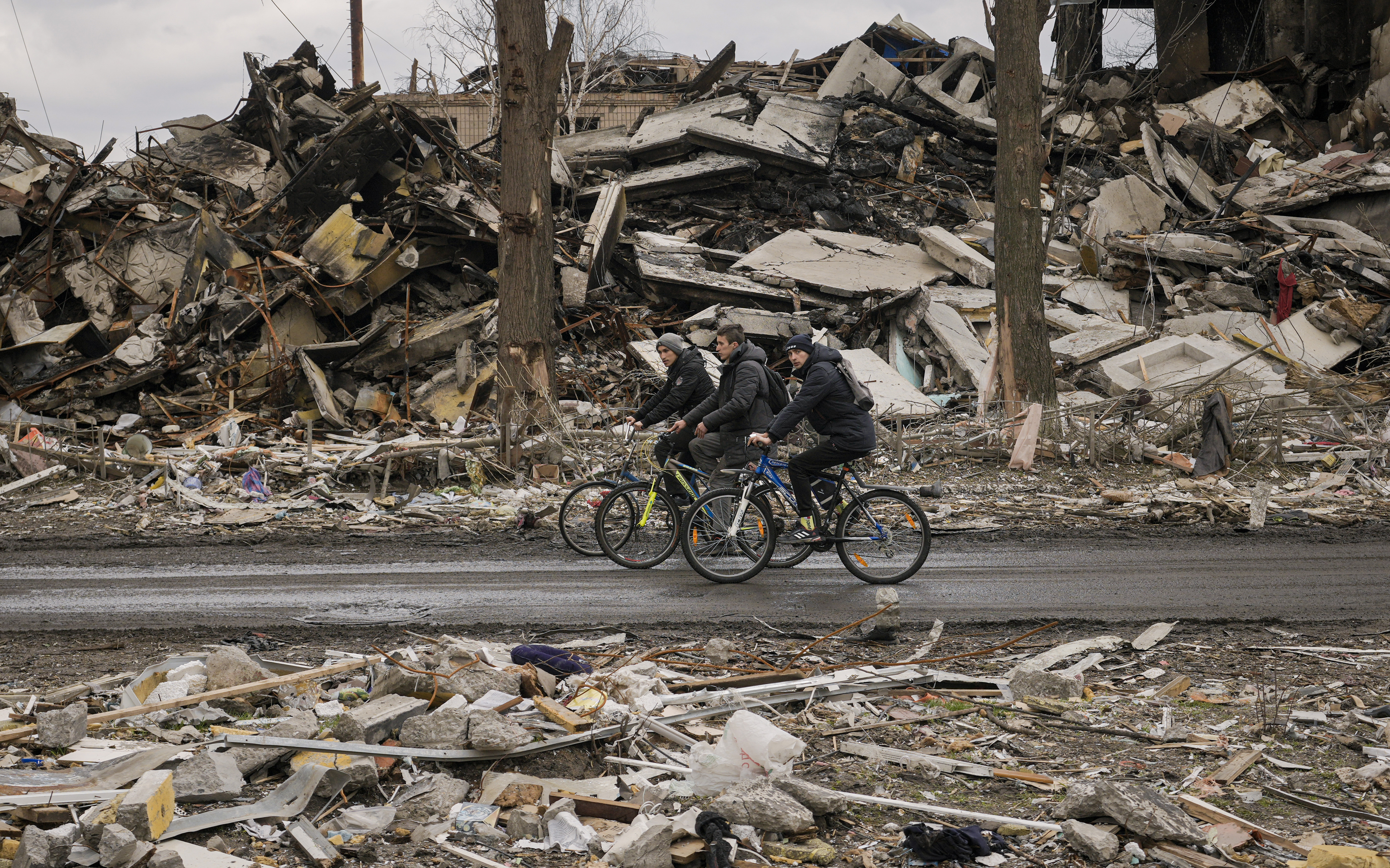 Men riding bicycle past destruction