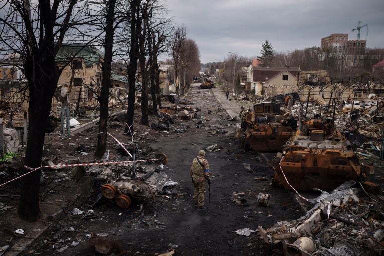 Ukrainian serviceman amid destroyed Russian tanks in Bucha