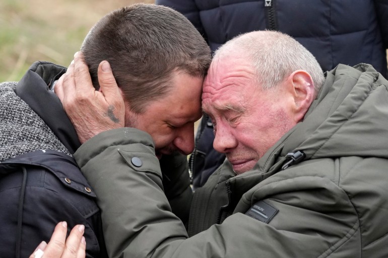Relatives cry at the mass grave of civilians killed during Russian occupation in Bucha, on the outskirts of Kyiv, Ukraine, Friday, April 8, 2022.