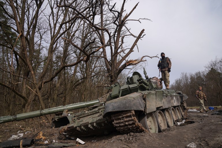 A Ukrainian soldier stands on a destroyed Russian tank in the n Chernihiv region,