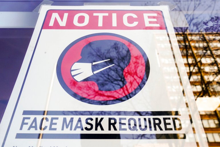 A sign requiring a mask as a precaution against the spread of the coronavirus at a store front in Philadelphia.